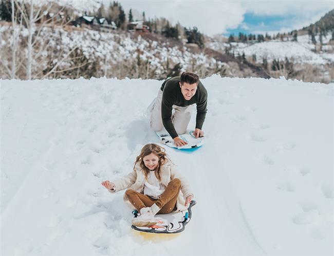 A father and daughter sledding on the slope