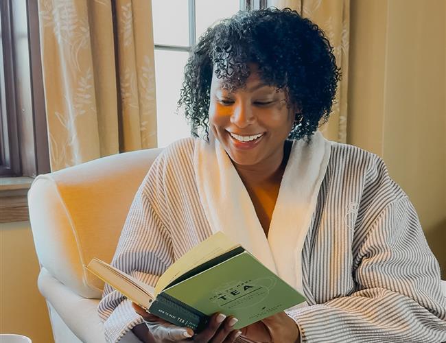 woman in relaxation lounge reading a book with a smile