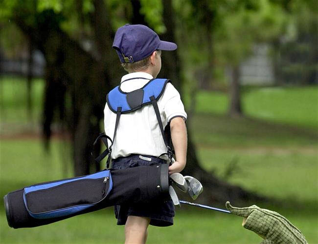 Young golfer walking on golf course with a bag 