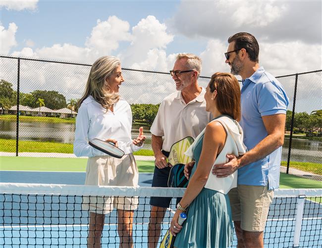 A group of people holding pickleball racquets on a pickleball court