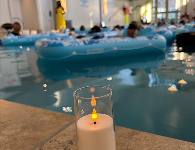 Glowing candle on the edge of pool during a floating sound bath session