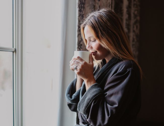 a woman wearing a plush robe and enjoying a beverage at the spa at hotel bennett