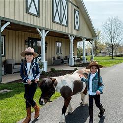 two young girls walk Cupcake the mini horse