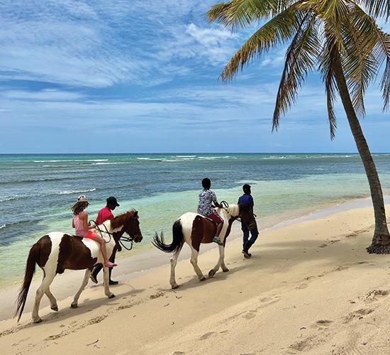people riding horses on beach