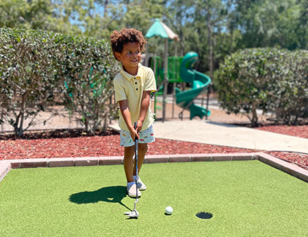 Young boy playing mini golf
