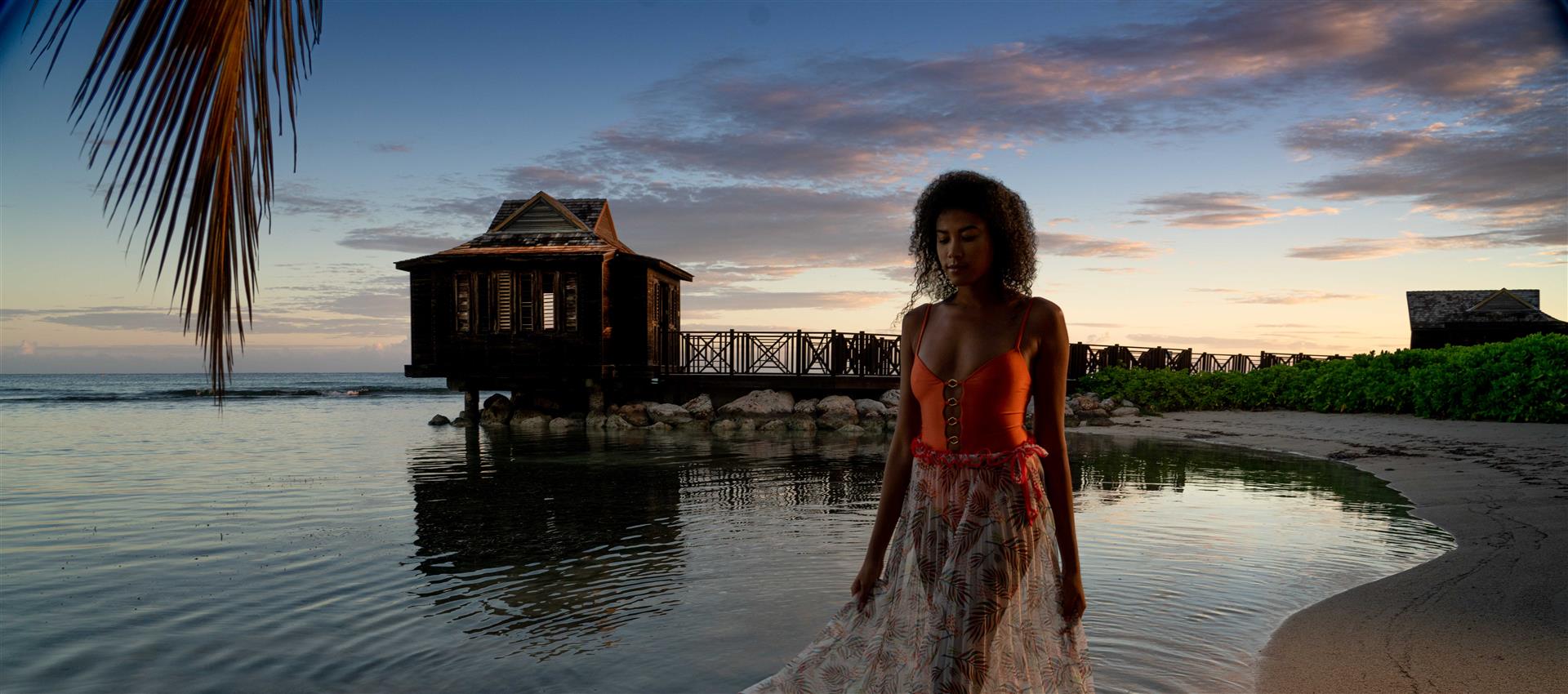 Woman walking along the beach at sunset