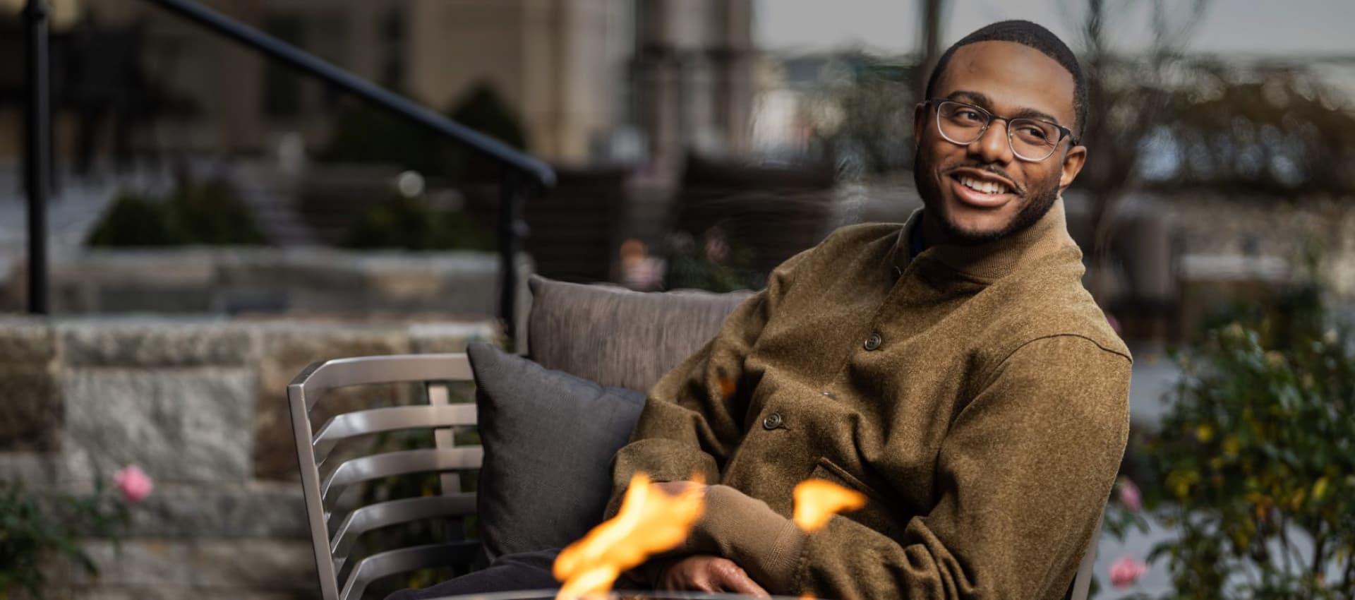 Kwame Onwuachi sitting by a fire pit